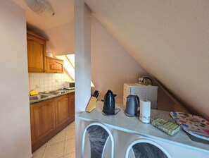 A small kitchenette with wooden cabinets, a microwave, a kettle, and a coffee maker.