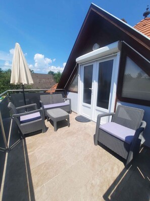 Eine Dachterrasse mit Korbmöbeln und einer Schiebeglastür.