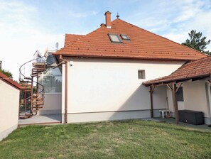 A house with a red-tiled roof, a visible chimney, a spiral staircase, and a small window.