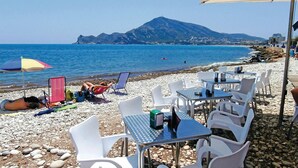 Un caffè sulla spiaggia con posti a sedere all'aperto, tavoli e ombrelloni.