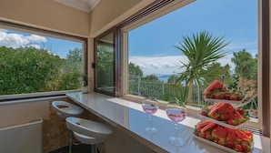 A balcony with a view of the sea, a table with glasses and a fruit platter, and a potted plant. - Luxurious home in Kastel Kambelovac with sauna (Kastel Kambelovac)
