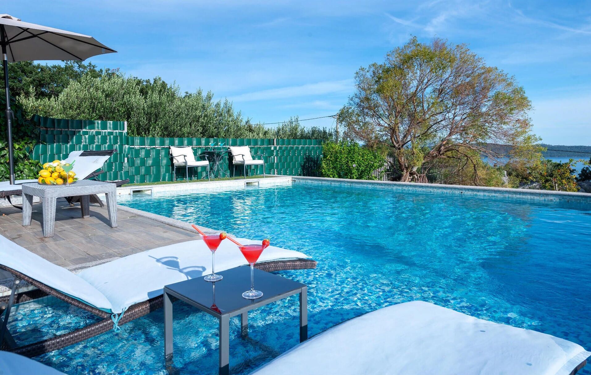 Une piscine avec des chaises longues et une table sur laquelle se trouve une boisson.
