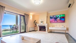 A spacious living room with a fireplace, a television mounted on the wall, and a balcony with a view of the sea. - Luxurious home in Kastel Kambelovac with sauna (Kastel Kambelovac)