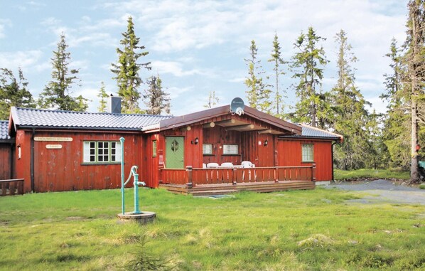 A wooden cabin with a porch, a satellite dish, and a well-maintained lawn.