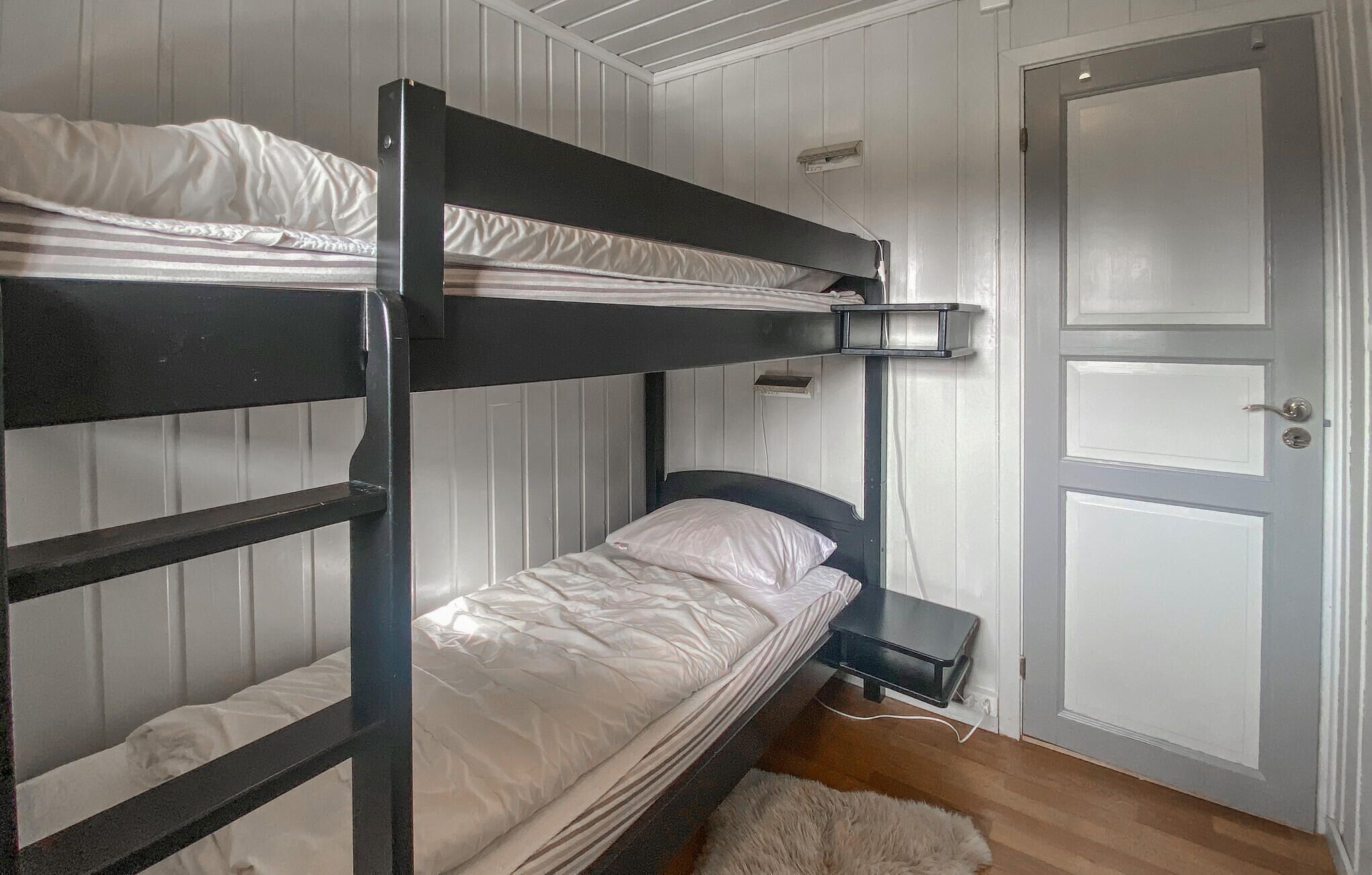 Habitación con literas, una puerta y una mesita pequeña.