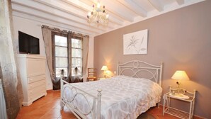 Ein Schlafzimmer mit Bett, Kommode, Fernseher und einer Chandelier.