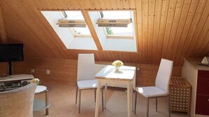 A cozy attic room with wooden walls, a small table with chairs, and skylights. - Apartment - Rügen-Fewo 291 (Sassnitz)