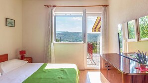 Een hotelkamer met een bed, een bureau, een stoel, een raam met uitzicht op het landschap en een balkon met een leuning.