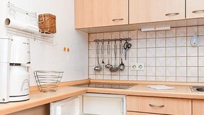A kitchen with wooden cabinets, a built-in microwave, and a hanging utensil rack. - Vacation apartment Treasure Island (Esens)