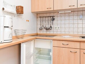 Una cocina con armarios de madera, microondas integrado y un colgador para utensilios.