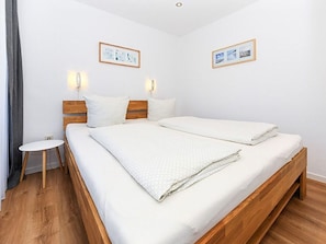 A double bed with a wooden frame, two bedside tables, and wall-mounted lights.