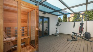 Eine Holzsauna mit Glastüren, einer hölzernen Sitzbank und einer Sitzbank mit Handtuch.
