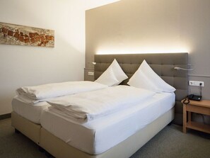 A hotel room with a double bed, a bedside table with a lamp, and a wall-mounted artwork. - Double Deluxe Plus - Hotel Goldenes Schiff (Bad Ischl)