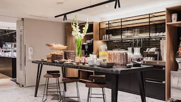 A modern kitchen with a central island, bar stools, and a variety of food items and kitchenware.