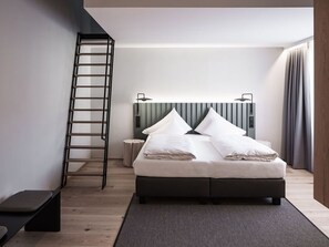 A modern bedroom with a bed, a ladder, a bedside table, and a headboard. - Double Deluxe Plus - Hotel Goldenes Schiff (Bad Ischl)