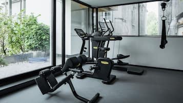 Ein Fitnessstudio mit Trainingsgeräten, großen Fenstern und Blick auf Grünflächen.