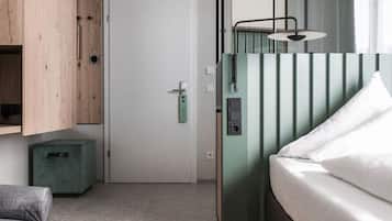 Ein Zimmer mit einem Bett, einem grünen Schrank, einem kleinen grünen Hocker und einer Tür.