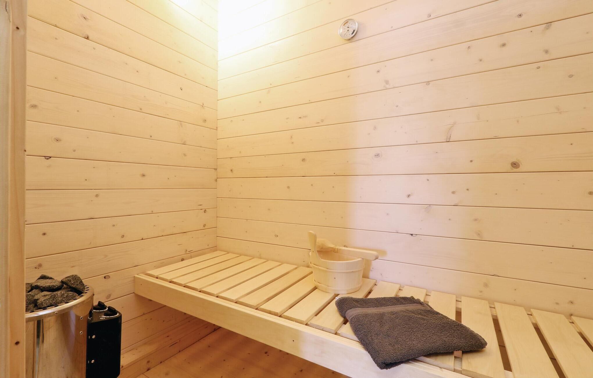 Una sala de sauna con bancos de madera, un balde y una toalla.