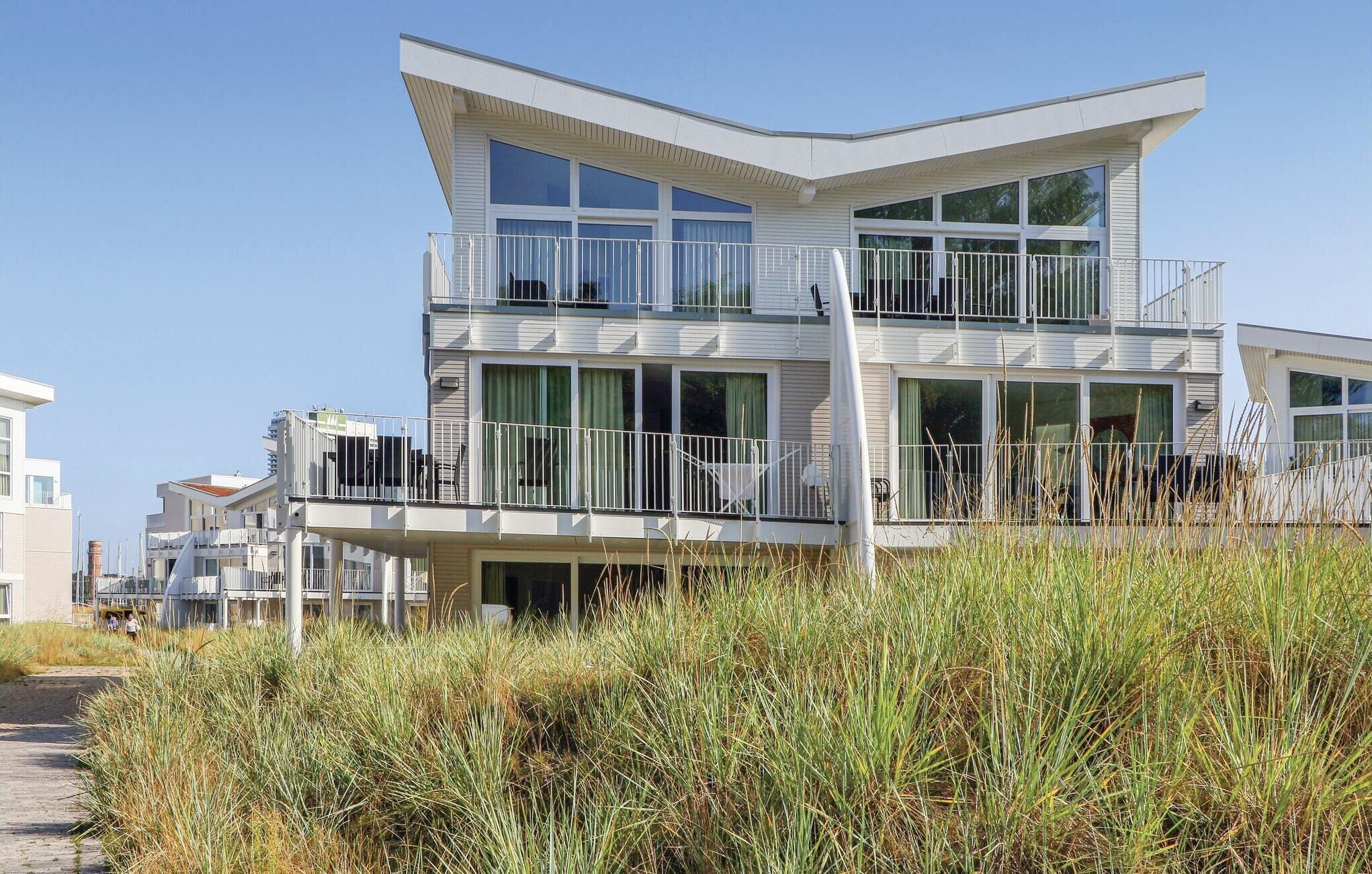 Un moderno edificio frente a la playa de dos pisos, con balcones, ventanas grandes y techo plano.