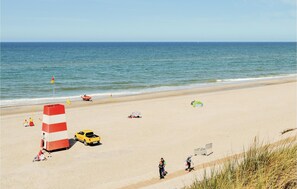 Una spiaggia con una torretta per i bagnini, un veicolo giallo e persone che si rilassano.