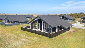 A row of modern, single-story houses with dark roofs and white trim, featuring large windows and a covered patio area. - Beach front home in Ringkøbing with sauna (Ringkøbing)