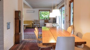 A dining area with a wooden table and chairs, a hanging light fixture, and a view of greenery through a window. - 4 bedroom lovely home in Græsted (Græsted)