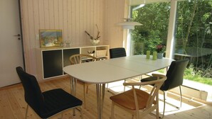 A dining area with a white table, four chairs, a painting, and a view of greenery through a window. - Stunning home in Rønne with kitchen (Rønne)