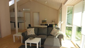 A cozy living room with a sofa, a small table, and a dining area with a table and chairs. - Stunning home in Rønne with kitchen (Rønne)