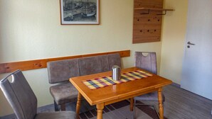 A dining area with a wooden table, two chairs, a bench, a framed picture, and a wooden panel with hooks. - Holiday Bungalow - Bungalow (Reinberg)