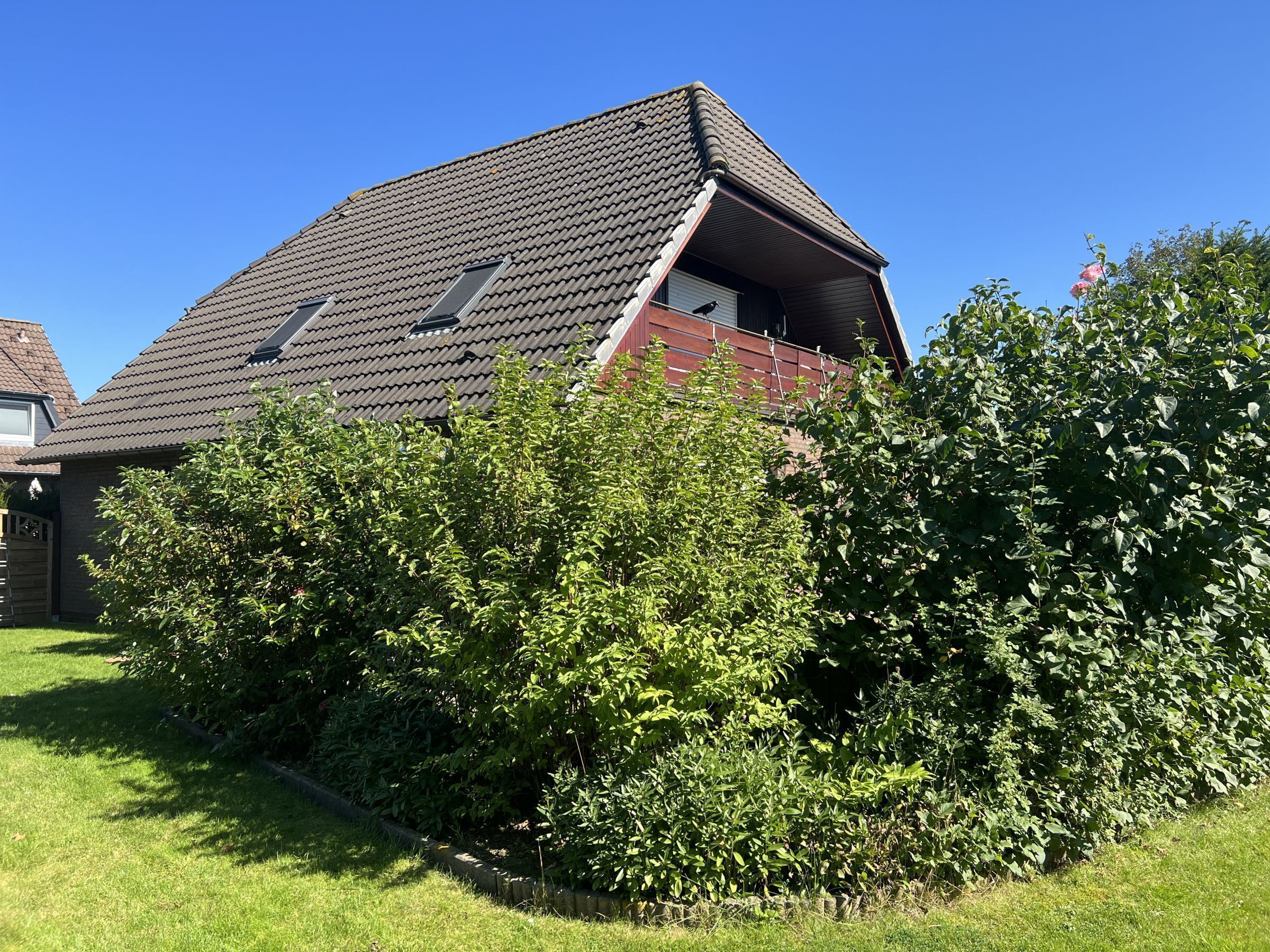 A house with a sloped roof, a visible attic window, and a red garage door.