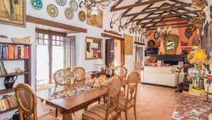 Un salón acogedor con una mesa de comedor de madera, sillas a rayas y una estantería llena de libros.