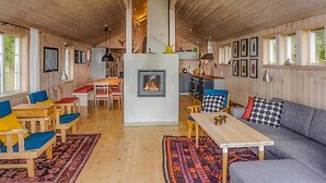 Ein gemütliches Blockhaus mit Kamin, Holzwänden und einem Essbereich.