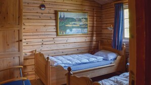 A wooden cabin room with a bed, a painting of a landscape, and a window with curtains. - Amazing home in Vikersund with sauna (Vikersund)