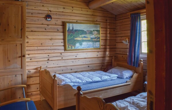Een houten kamer met een bed, een landschapsschilderij en een raam met gordijnen.