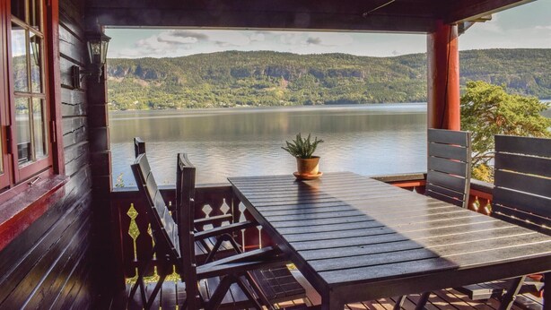 A wooden deck with a table and chairs overlooking a lake and forested hills. - Amazing home in Vikersund with sauna (Vikersund)