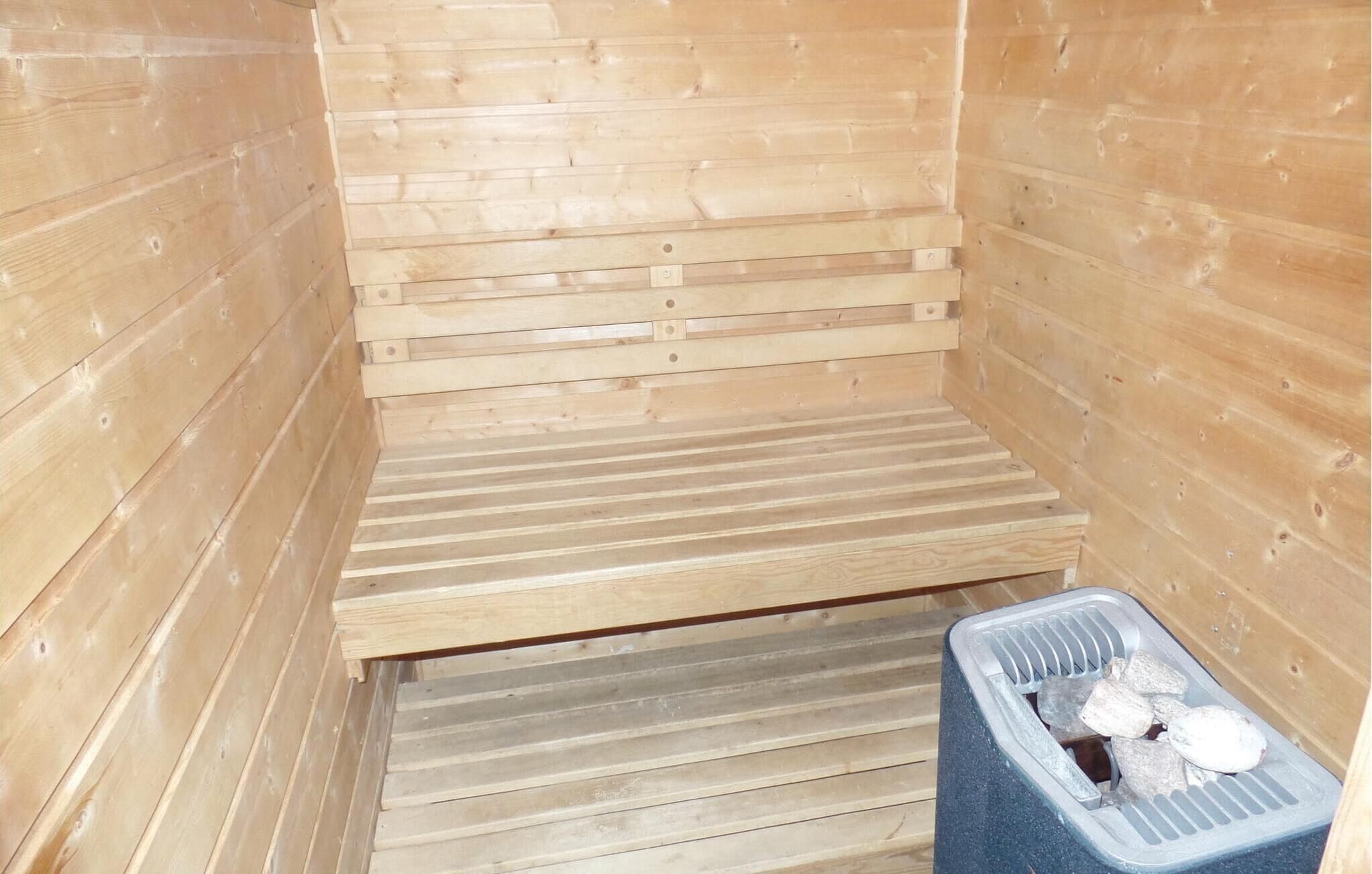 A sauna room with wooden walls and a bench.