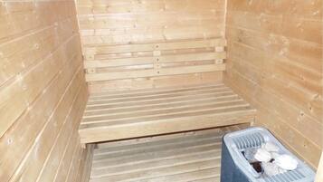 A sauna room with wooden walls and a bench.
