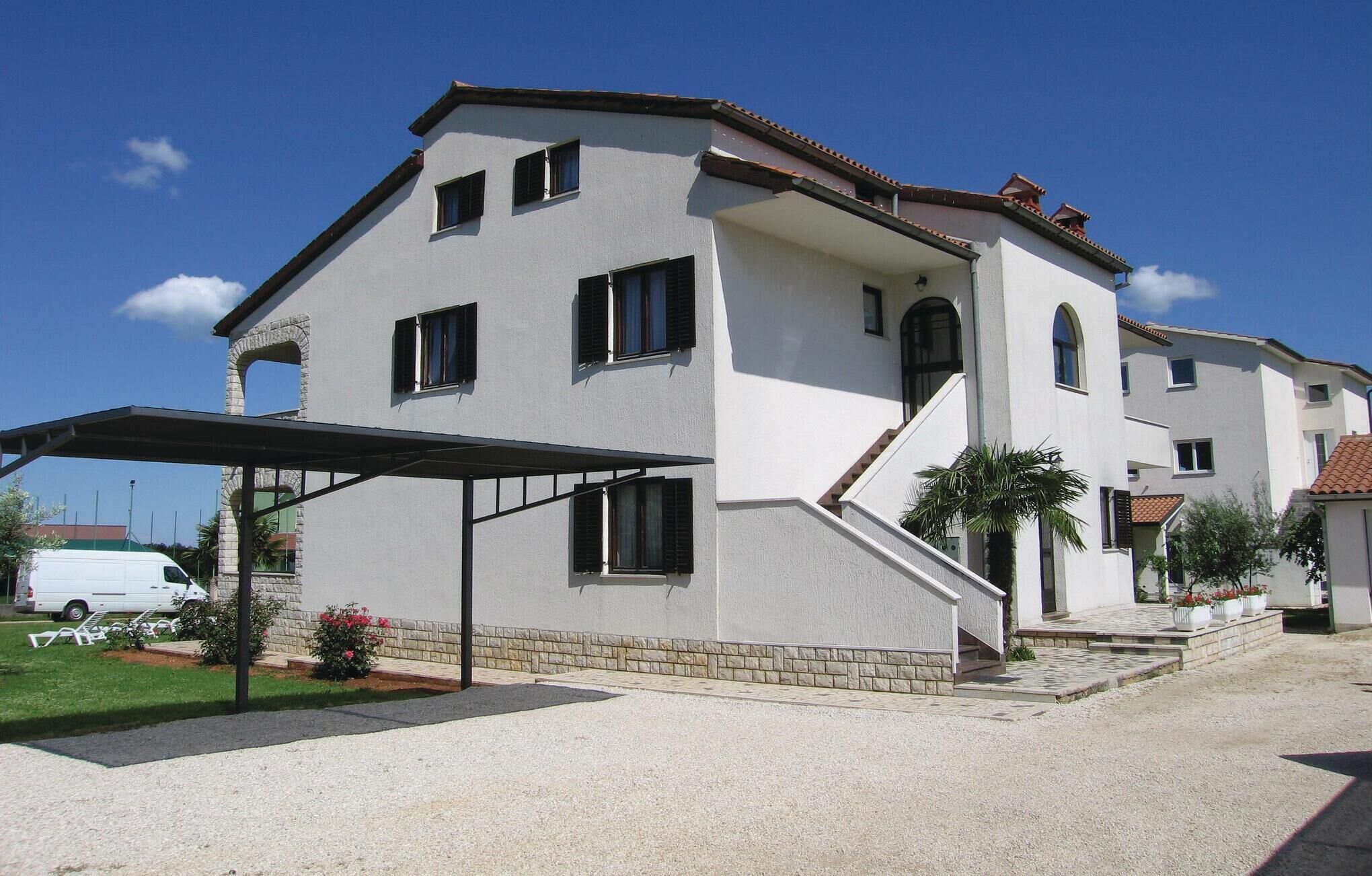 A two-story building with a covered patio, a staircase, and a white exterior.