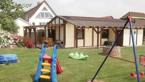 A house with a patio, a swing set, and a slide in the yard.