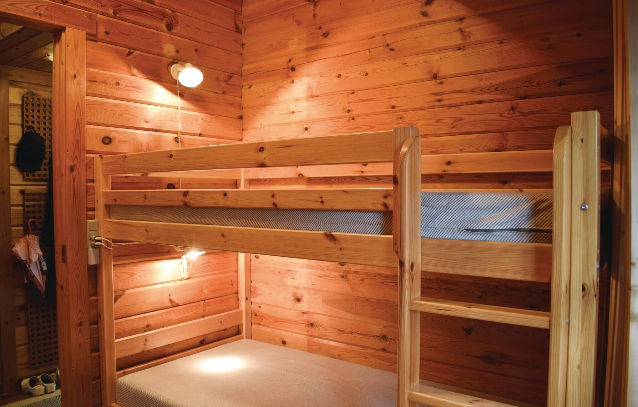 A wooden cabin interior with a bunk bed, a ladder, and a small window.
