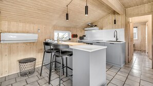 A modern kitchen with wooden walls, a central island, bar stools, and pendant lighting. - Awesome home in Hvide Sande with sauna (Hvide Sande)