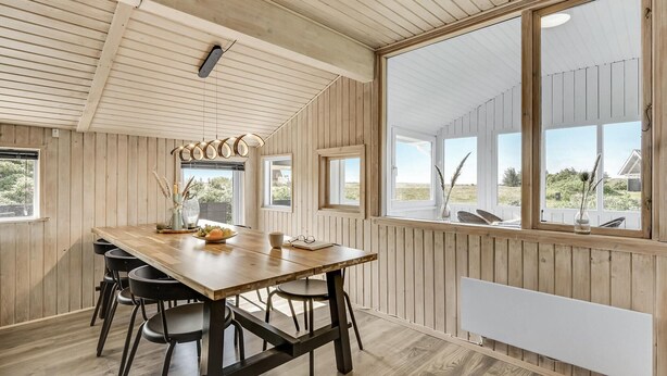 A wooden-paneled room with a large table, chairs, and a view of the outdoors. - Awesome home in Hvide Sande with sauna (Hvide Sande)