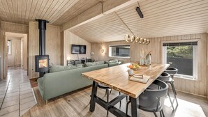 A modern interior with a wooden ceiling, a central dining table, a green sofa, and a fireplace. - Awesome home in Hvide Sande with sauna (Hvide Sande)