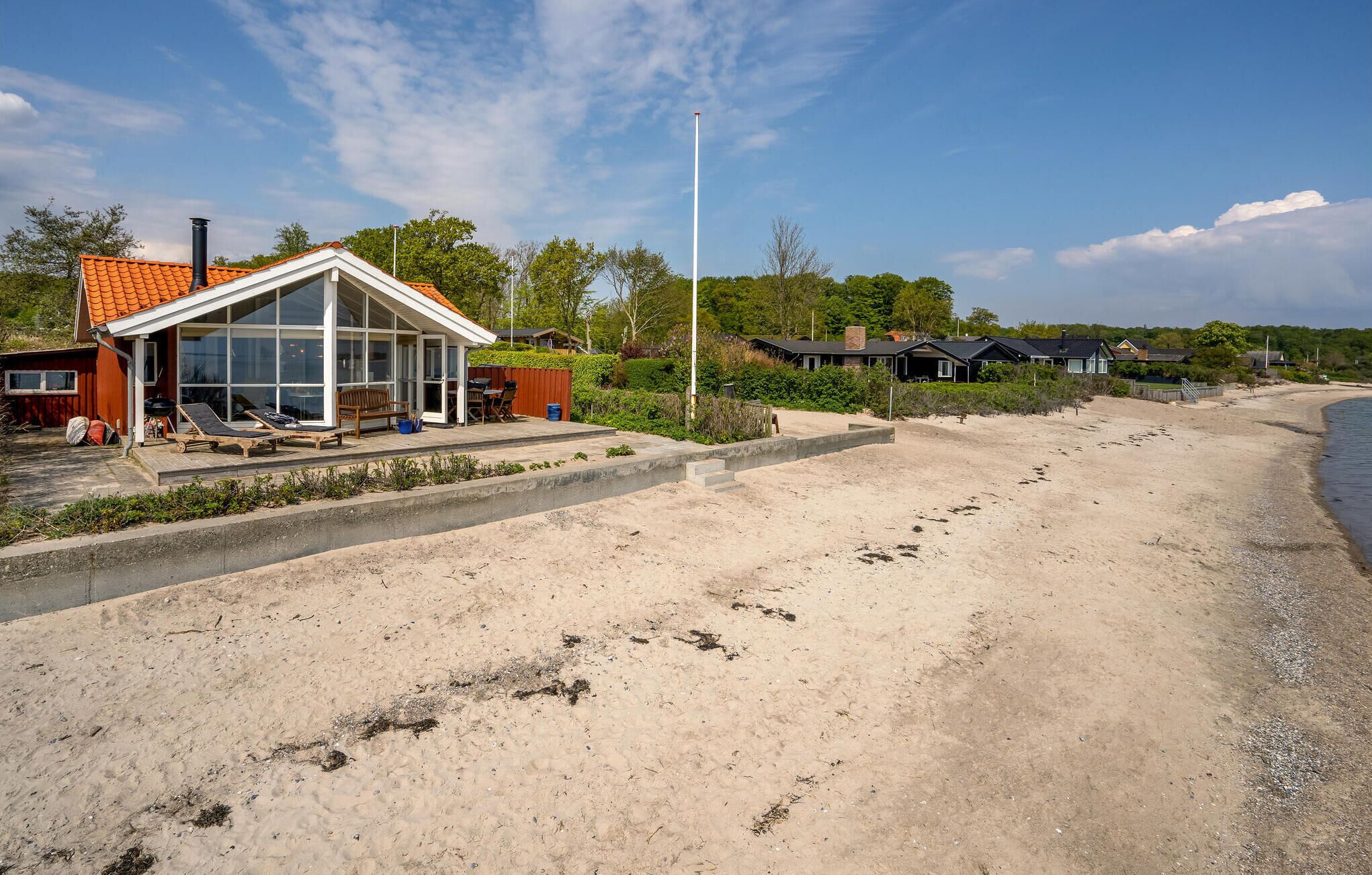 A beachside property with a glass-enclosed patio, a barbecue area, and a sandy beach.