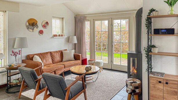 A cozy living room with a sofa, chairs, a coffee table, a fireplace, and a large window with a view of the outdoors.