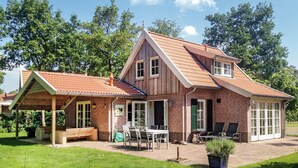 A two-story house with a brick exterior, a sloped roof, and a covered patio area with outdoor furniture.
