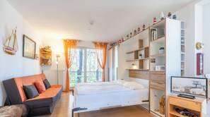 Een slaapkamer met een bed, een bank, een televisie en een boekenkast.