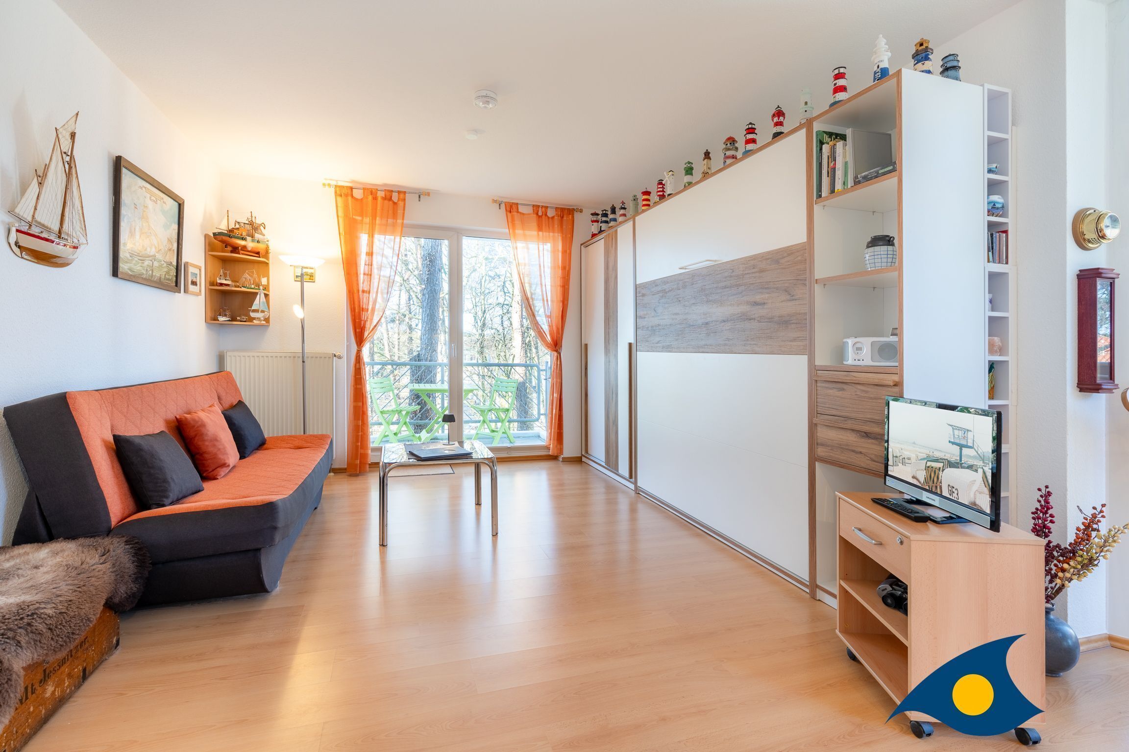 A modern living room with a sofa, a TV stand, a bookshelf, and a window with curtains.