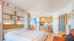 Een moderne hotelkamer met een bed, een bureau, een stoel, een kitchenette en een eettafel.