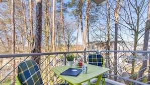 En balkon med et bord, stole og en bærbar computer.
